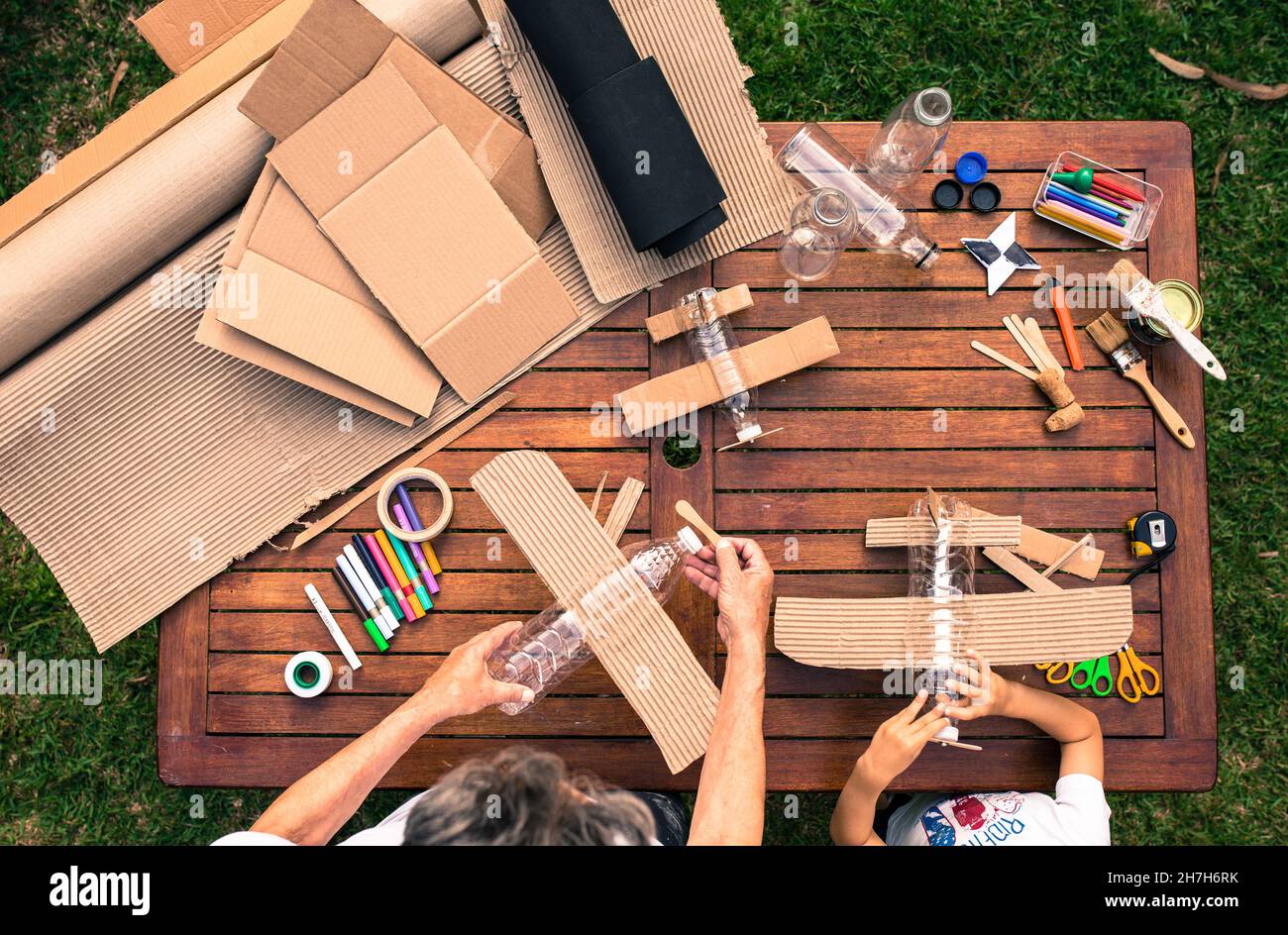 grandfather and grandson building airplanes with recycled material (cardboard, PVC bottles, wood). work ideas circular economy, recycling, environment Stock Photo