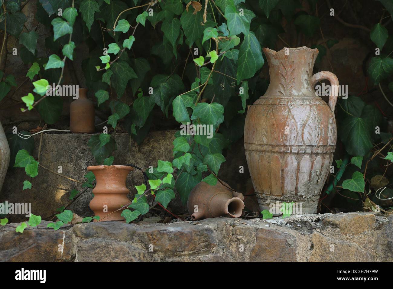 Lebanese terracotta jars in the garden among green leaves. Stock Photo