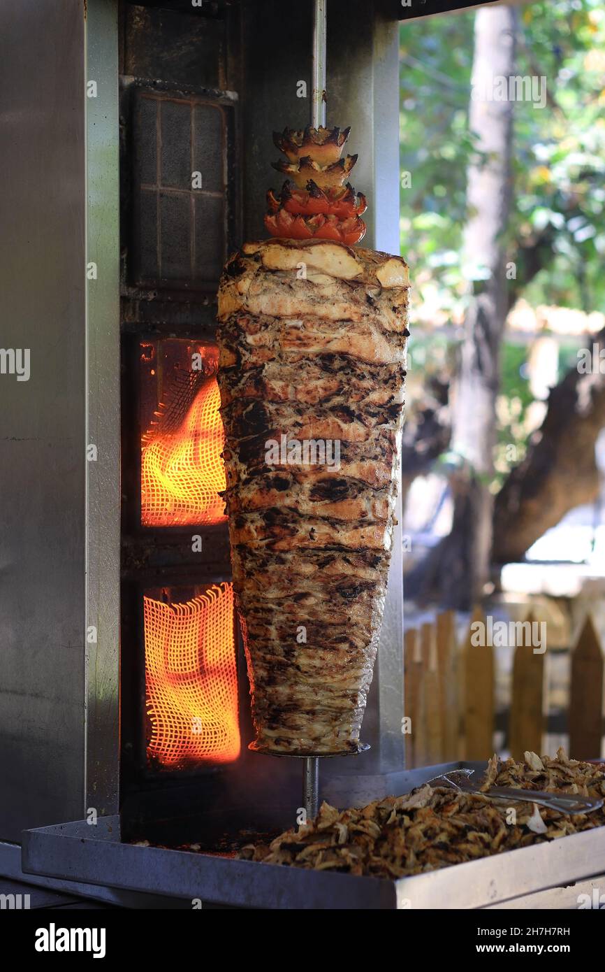 A chicken shawarma skewer roasting on a rotating pole. Stock Photo