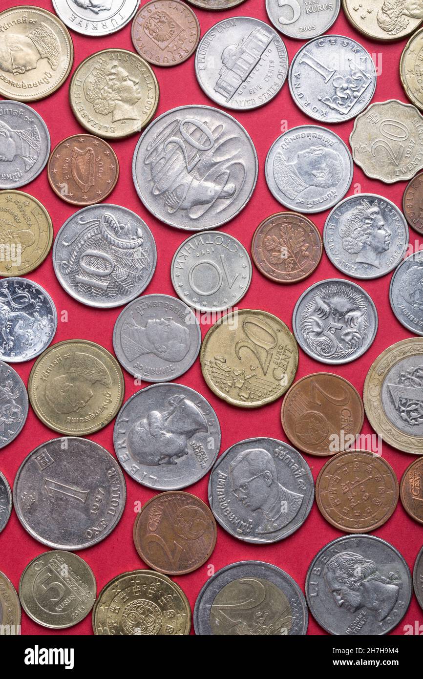 Coins of different countries on a red background. Stock Photo