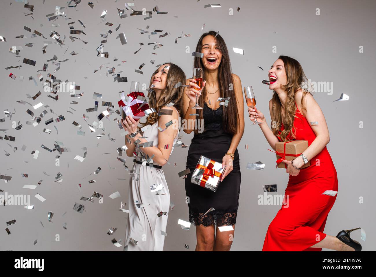Three girls with drinks having fun under confetti Stock Photo - Alamy