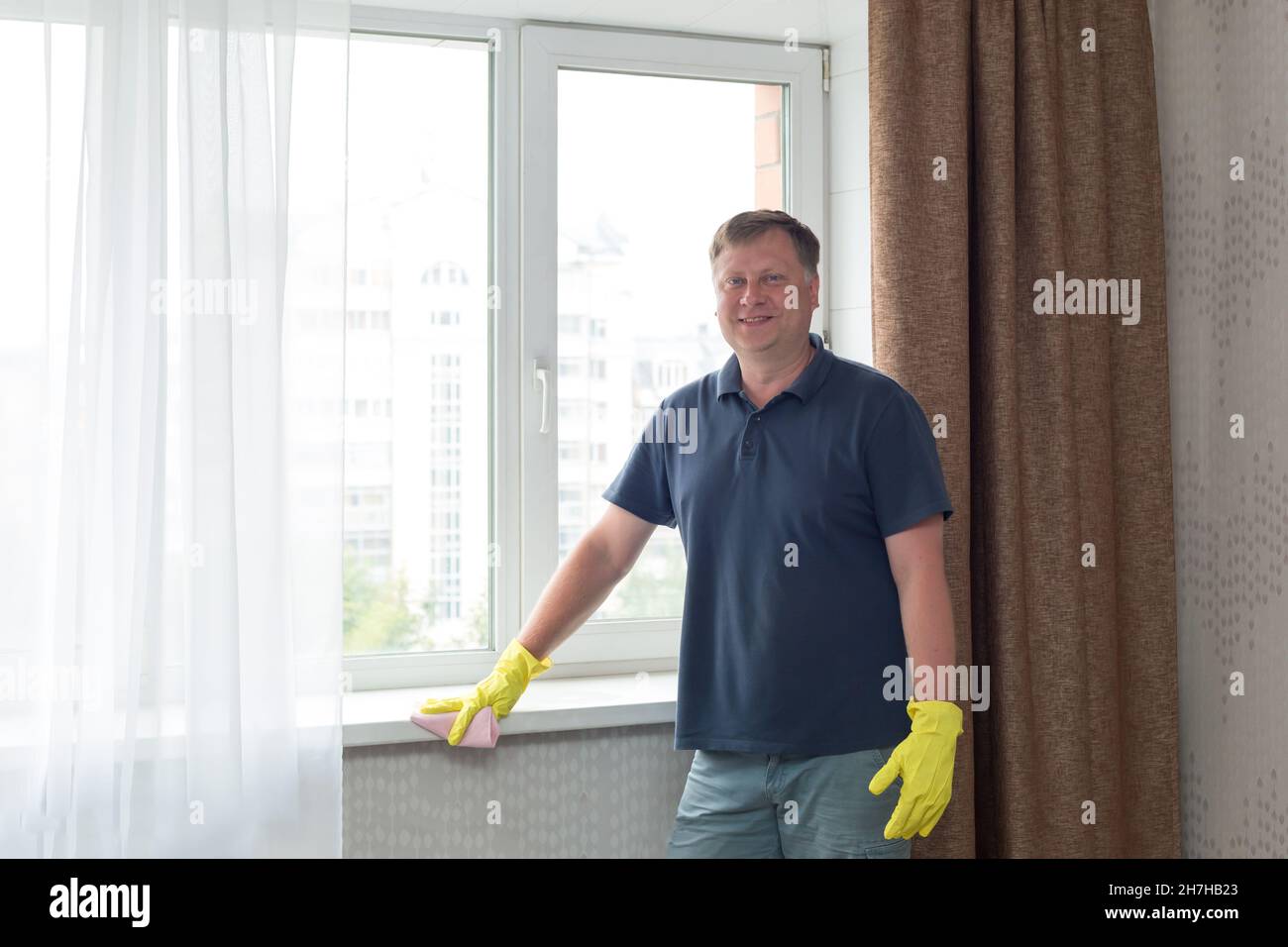 https://c8.alamy.com/comp/2H7HB23/a-man-cleans-his-apartment-wipes-windowsill-in-yellow-rubber-gloves-2H7HB23.jpg