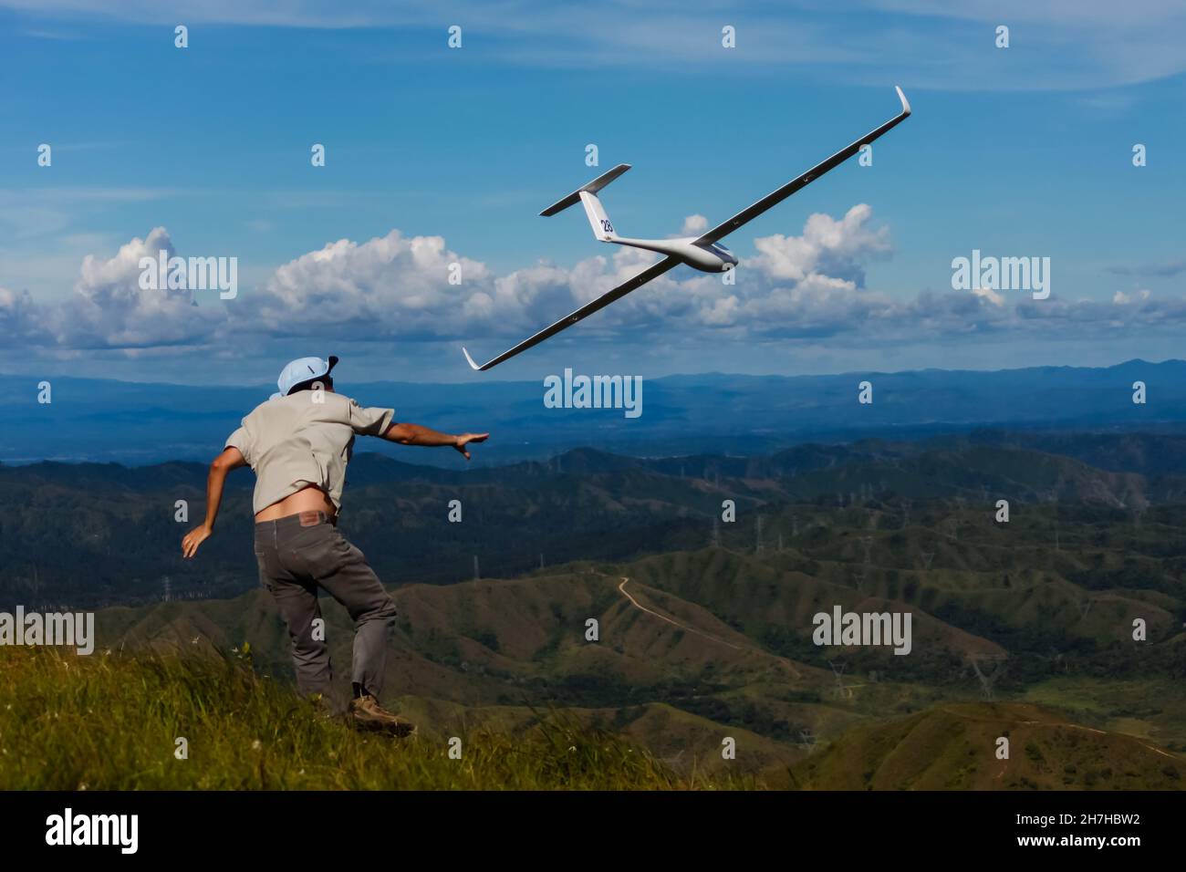 Launch of hillside glider, model airplane, with mountain landscape