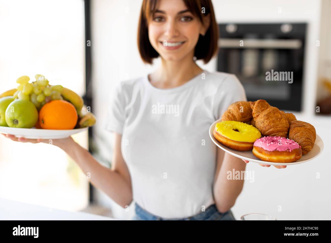 Healthy diet vs junk food. Pretty lady holding fruits and doughnuts