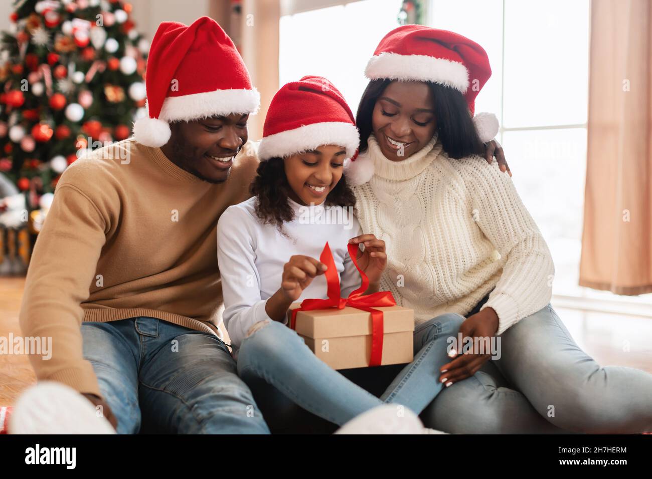 Happy black girl celebrating Christmas unwrapping gift box Stock Photo