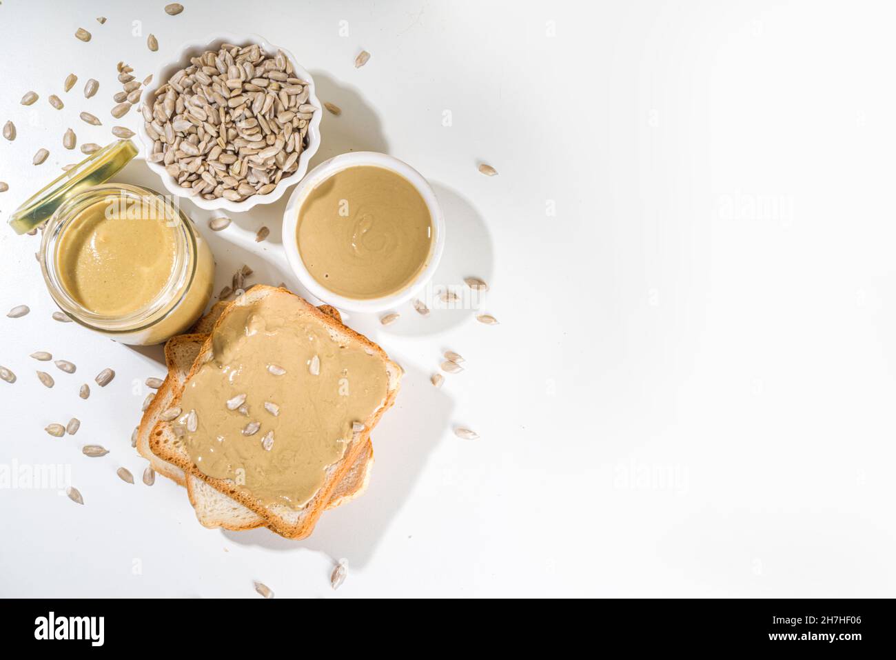 Sunflower seeds butter in small bow, jar and spoon. Modern alternative