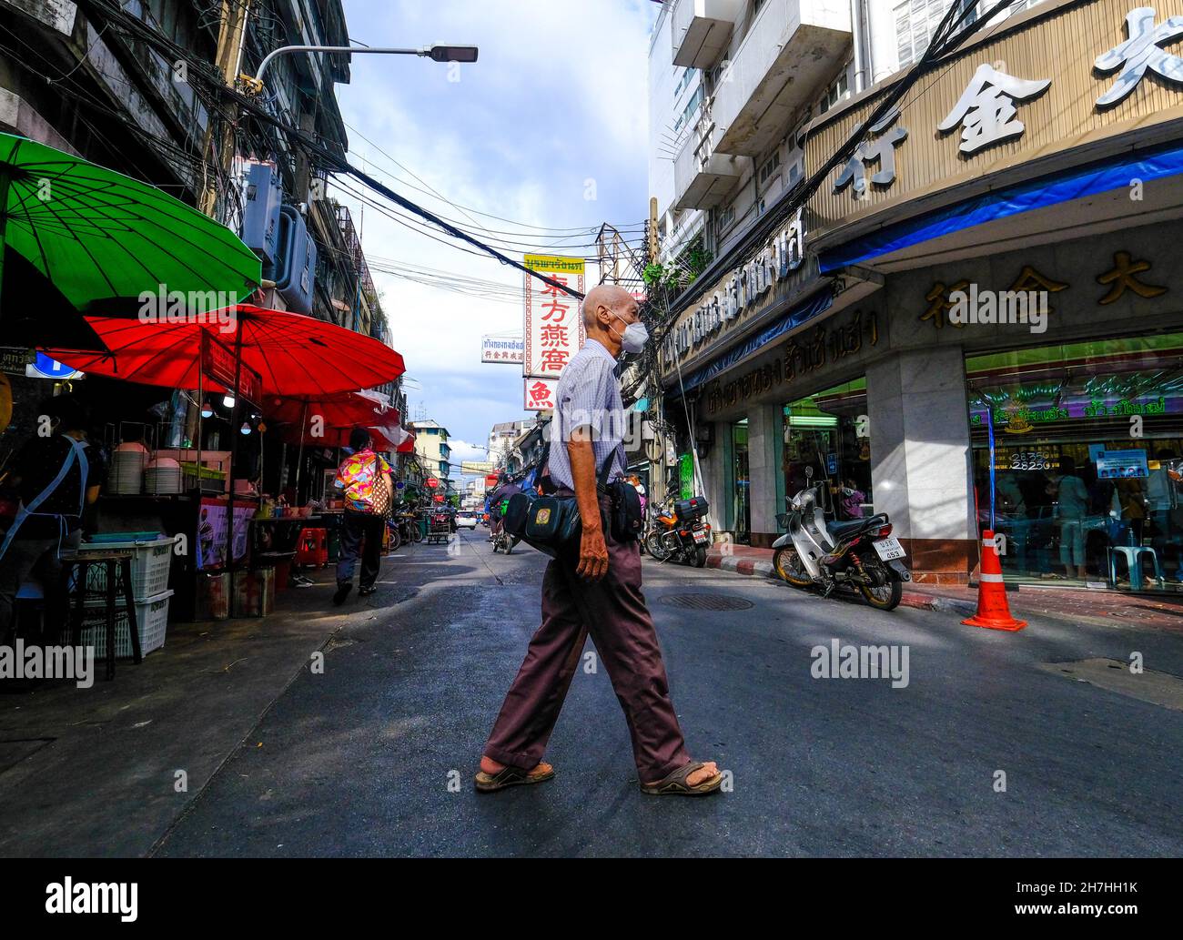 An elderly man crosses the road in Chinatown, Bangkok, Thailand. Stock Photo