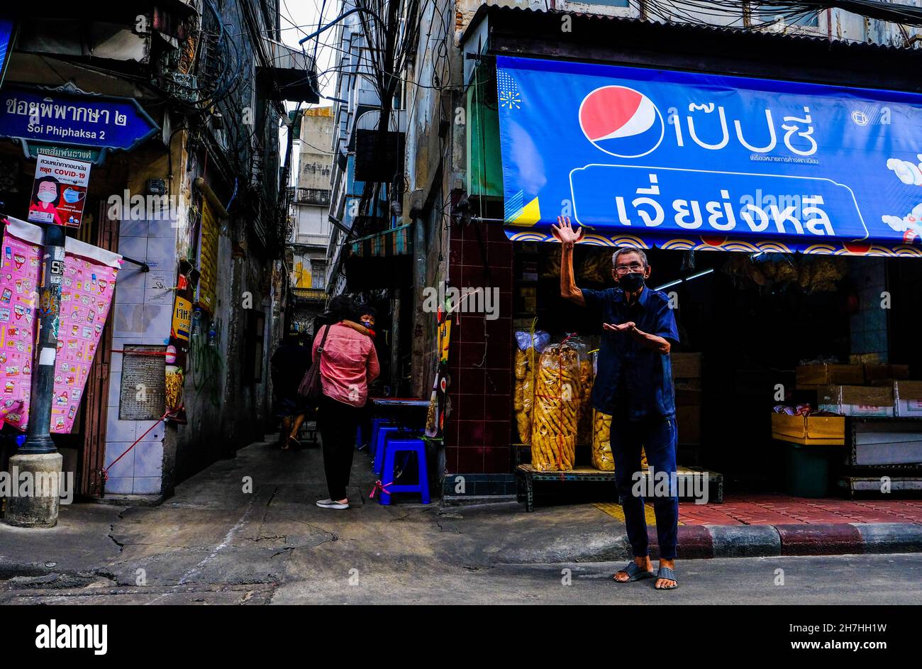 An elderly man makes a gesture in a street in Chinatown, Bangkok, Thailand. Stock Photo