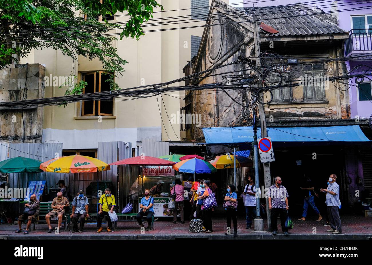 People of all ages wait at a bus stop in Chinatown, Bangkok, Thailand Stock Photo