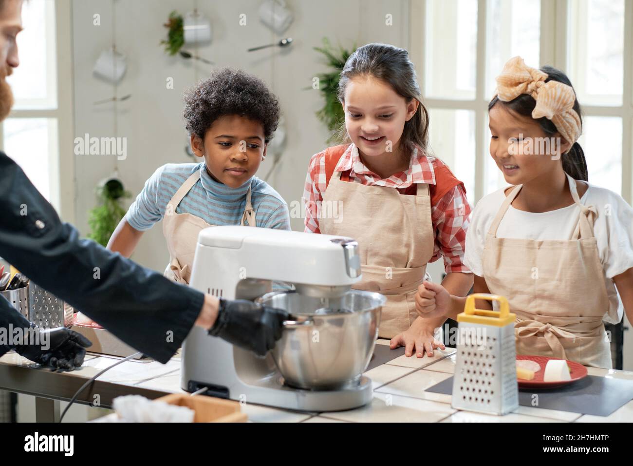 Cook making dough in mixer and teaching children to cook during his masterclass in the kitchen Stock Photo