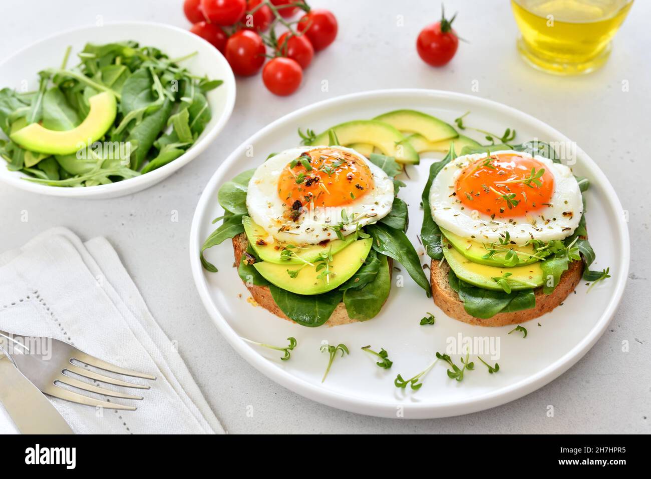 Bread with fried eggs, avocado and greens, close up Stock Photo