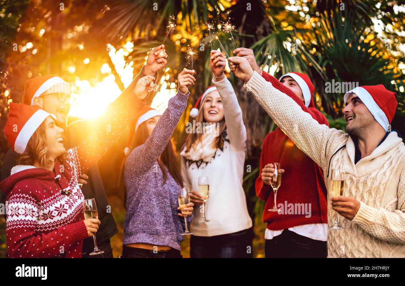 Young friends with santa hats celebrating Christmas with champagne wine toast outdoors - Tropical holidays concept with people group enjoying time Stock Photo