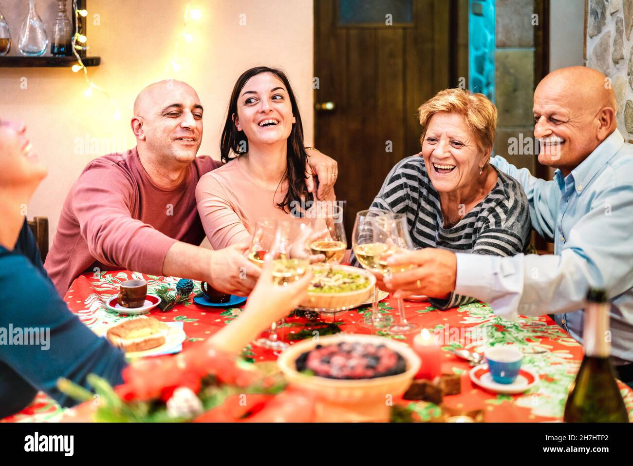 Mixed age group toasting white wine and having fun at winter holiday reunion - Dinner celebration concept with happy adult friends Stock Photo
