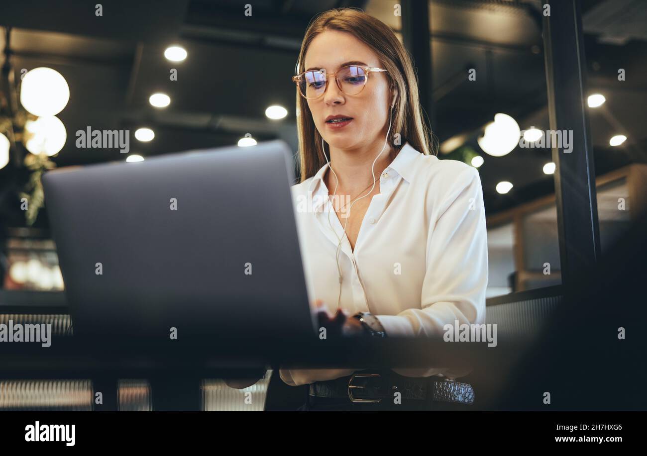 Woman typing on a laptop in a modern workspace. Focused young ...