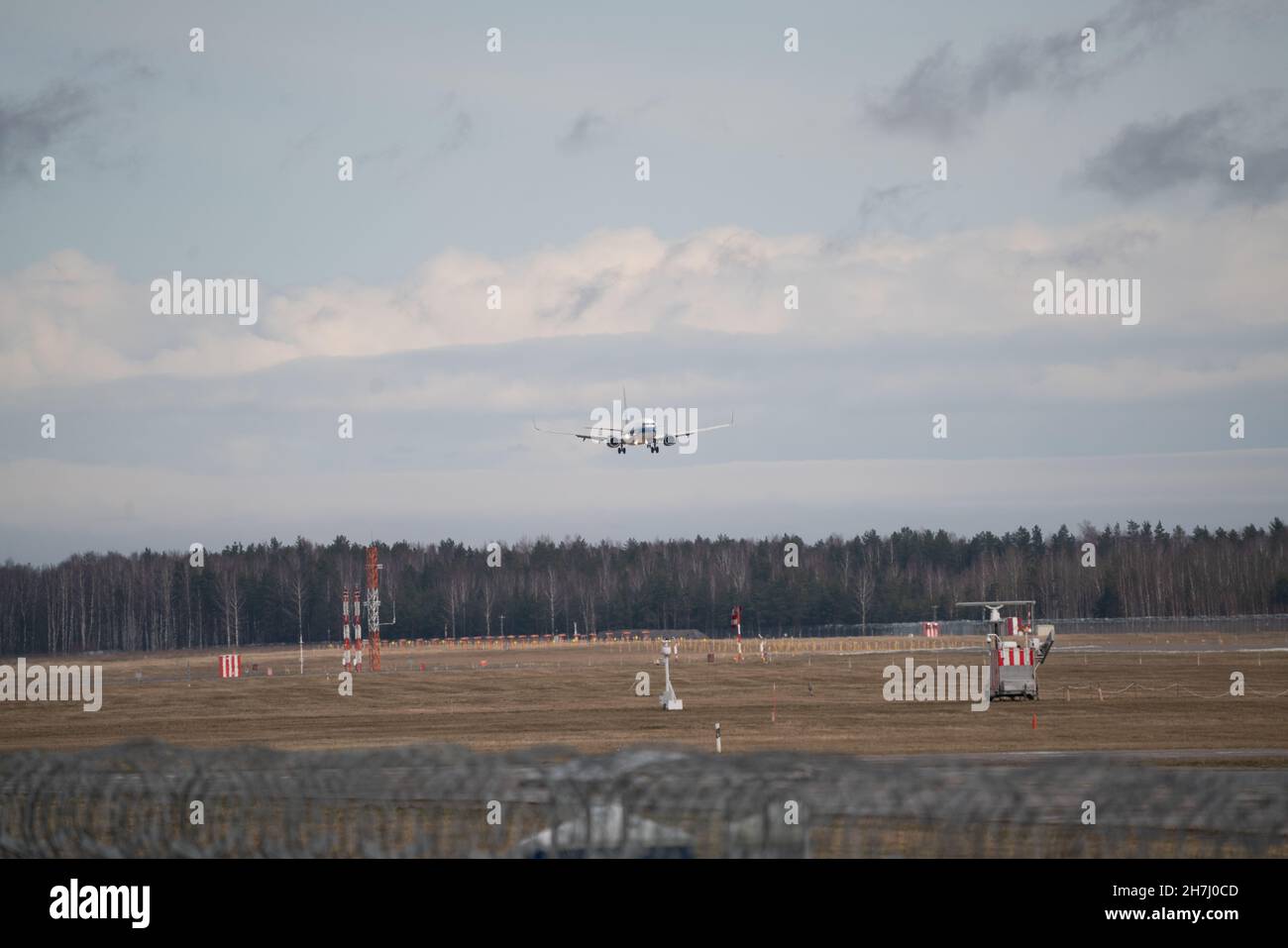 airplane is landing at airport against blue cloudy sky Stock Photo - Alamy