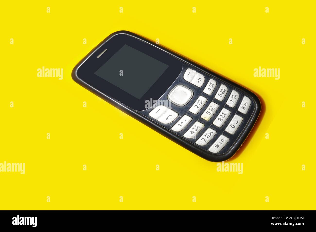 vintage mobile phone with copyspace on yellow background. Stock Photo