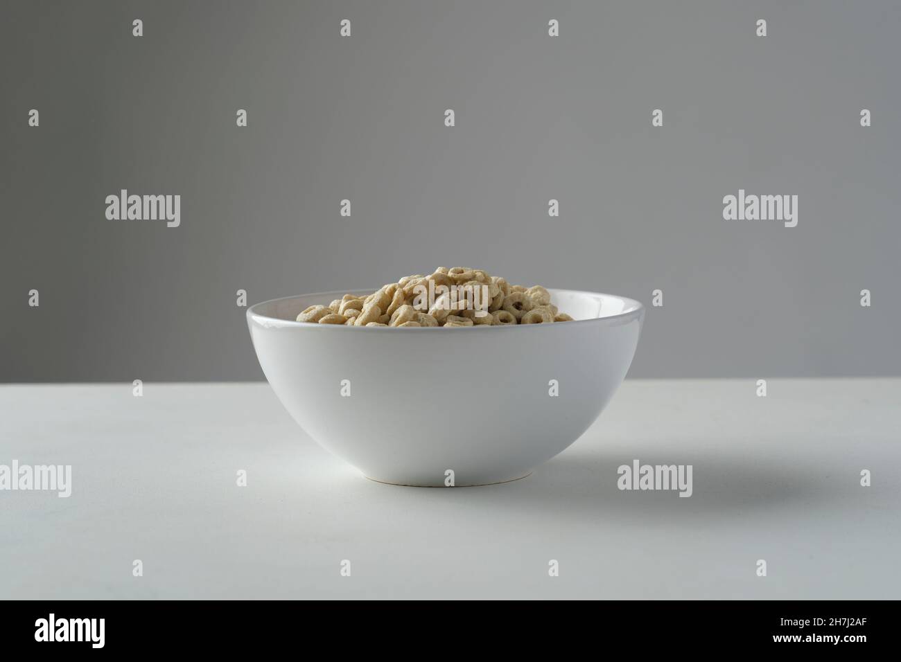 Loop cereals in a white bowl on a white table with grey background Stock Photo