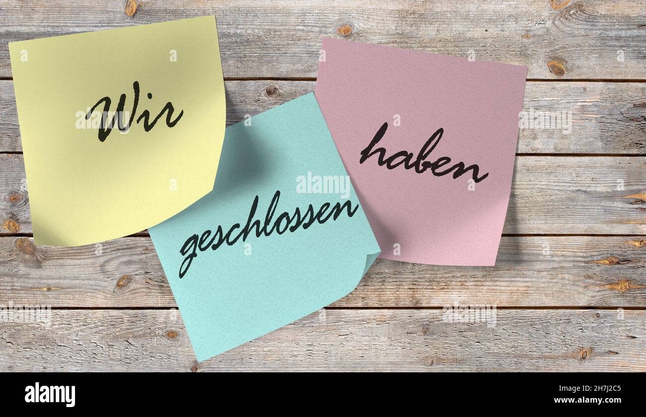 Sticky notes with the words 'Wir haben geschlossen', translation 'We are closed' on a wooden wall Stock Photo