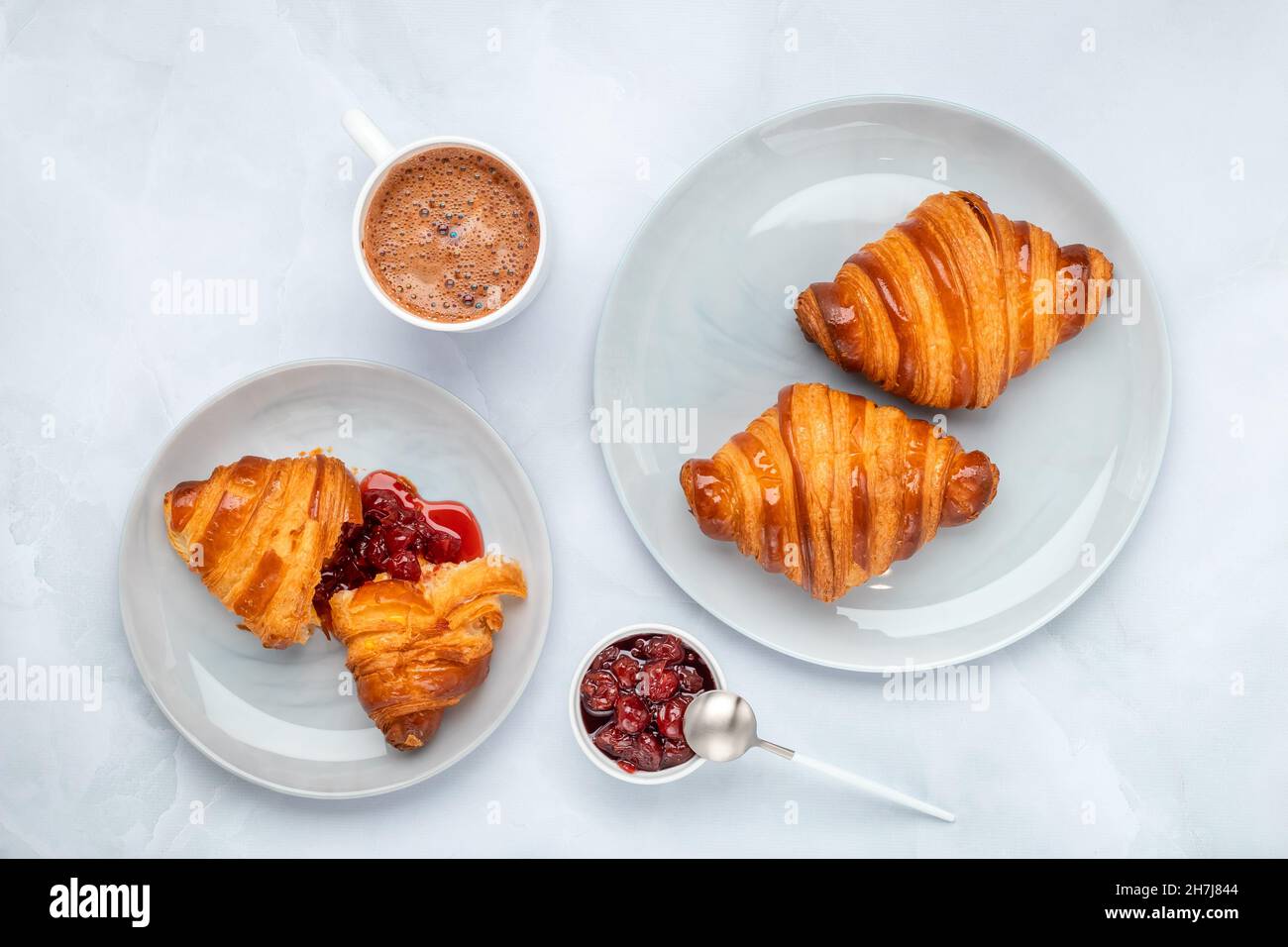 Croissants and jam. Two gray plates on a marble table. Top view, flat lay. A cup of cocoa in the morning for breakfast. Traditional French cuisine. Fo Stock Photo