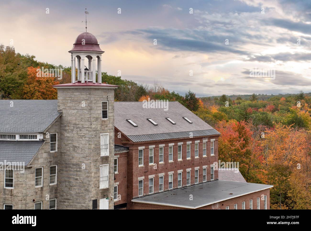 Beautiful sky and colorful autumn scene in historic town of Harrisville, New Hampshire. Old bell tower and preserved textile mill buildings. Stock Photo