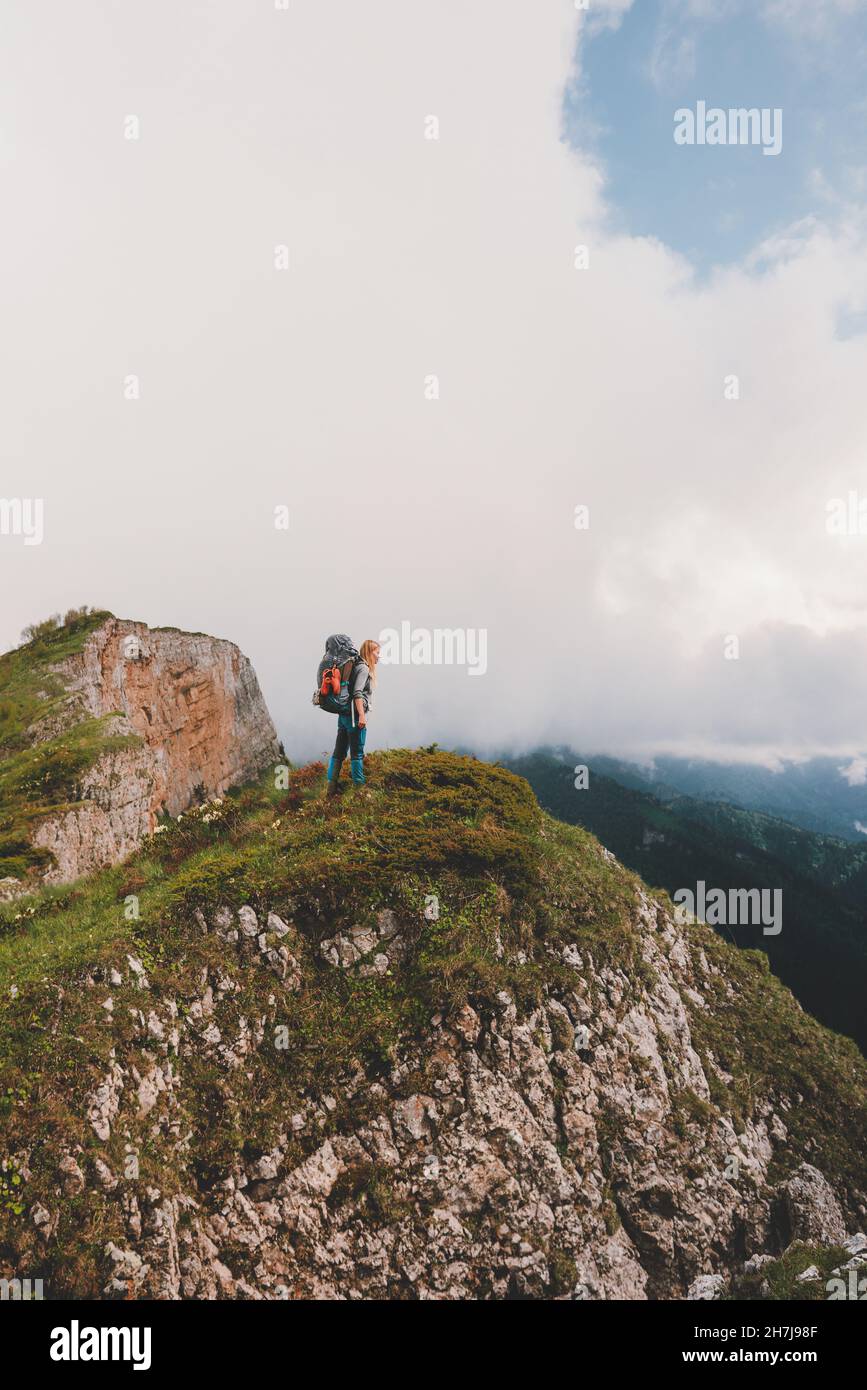 Backpacker climbing mountains travel adventure vacations outdoor active healthy lifestyle woman standing on cliff edge Stock Photo