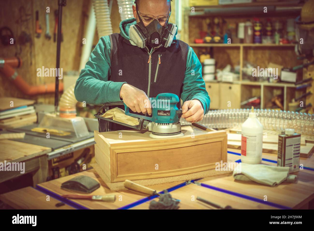 man uses an orbital sander in his workshop. Stock Photo