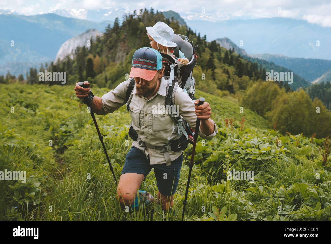 Father hiking carrying child in backpack family traveling together in mountains healthy lifestyle adventure tour summer active vacations outdoor Stock Photo