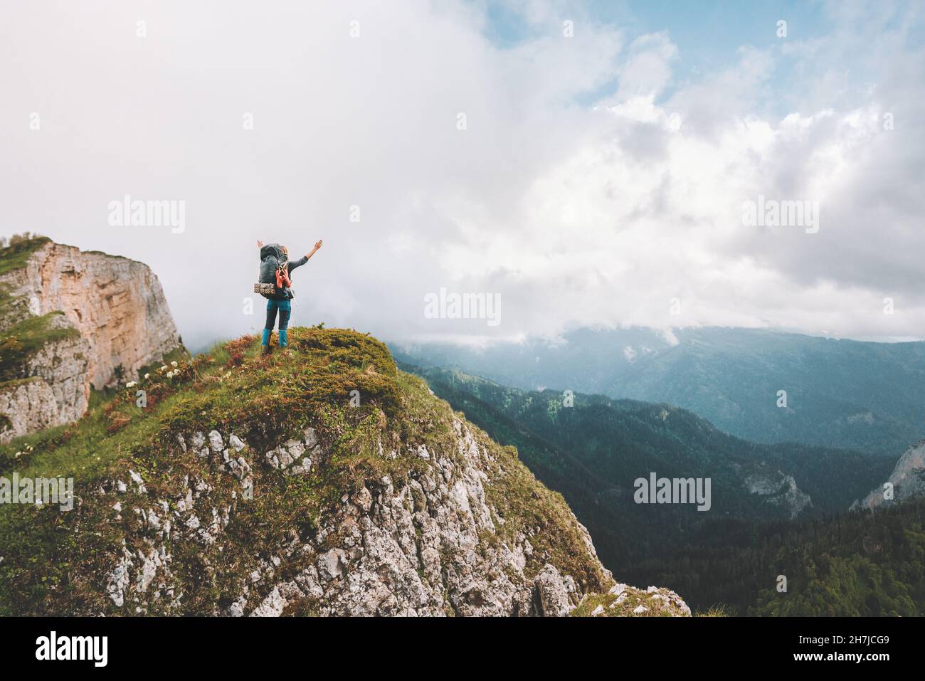 Traveler hiking on mountain top success raised hands travel adventure vacations outdoor active healthy lifestyle survival concept Stock Photo