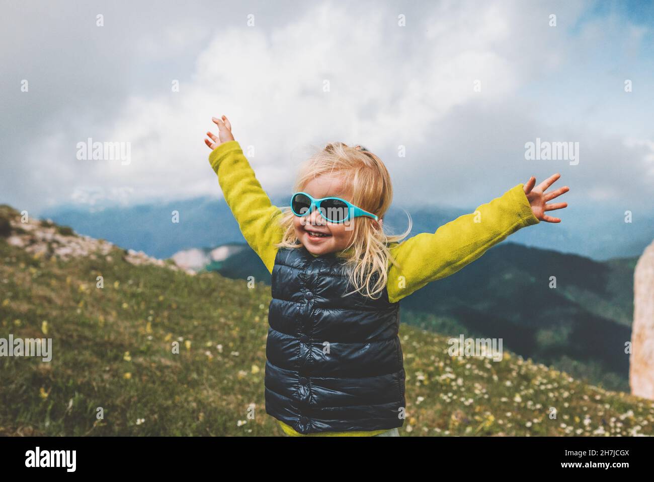 Child happy raised hands walking in mountains travel family vacations lifestyle 2 years old laughing toddler outdoor funny kids Stock Photo
