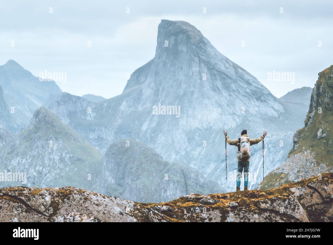 Man hiking in Norway traveler happy raised hands enjoying mountain view traveling backpacking outdoor active healthy lifestyle hobby climbing extreme Stock Photo