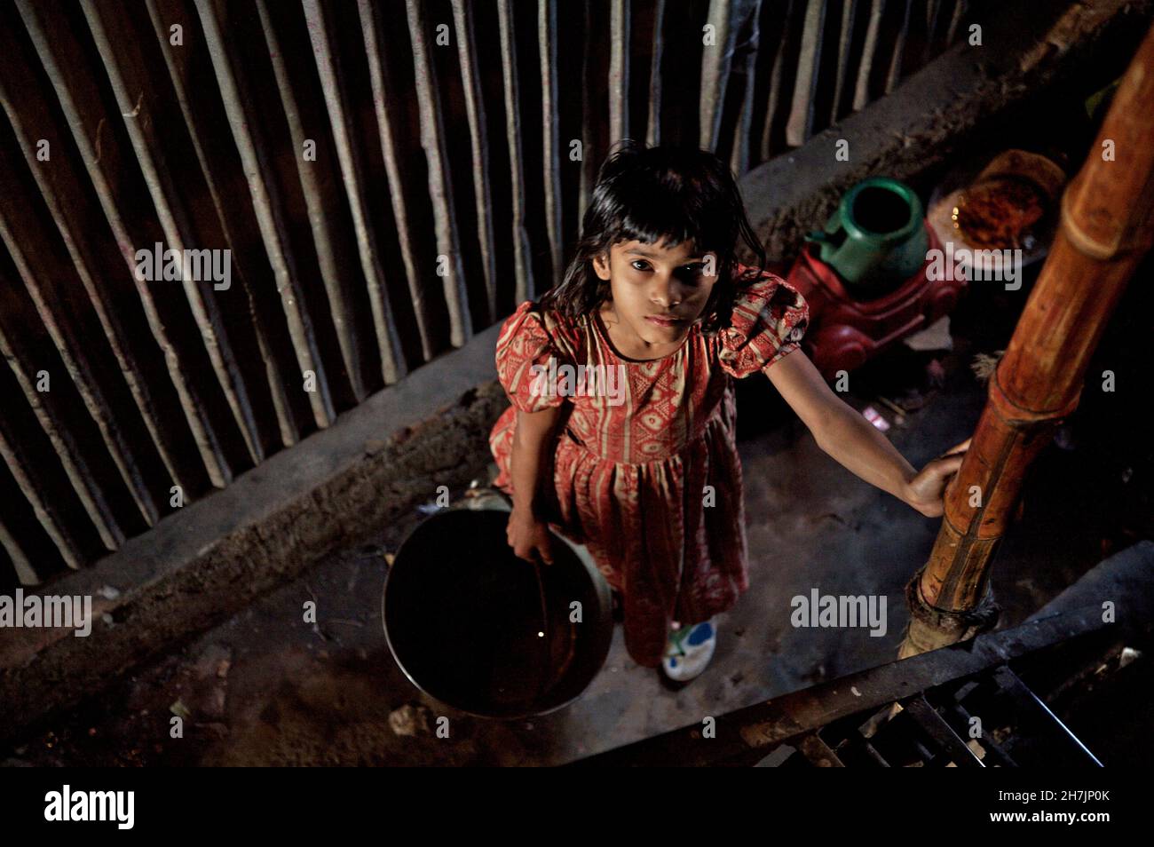 A child holds a bucket full of water, collected from the communal hand pump, at a slum, near the Buriganga river, in Old Dhaka, Bangladesh. February 2 Stock Photo