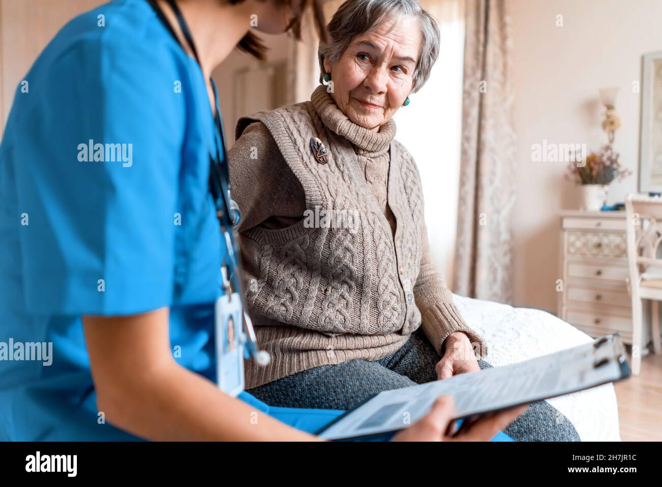 Young nurse is caring for an elderly 80-year-old woman at home, Stock Photo