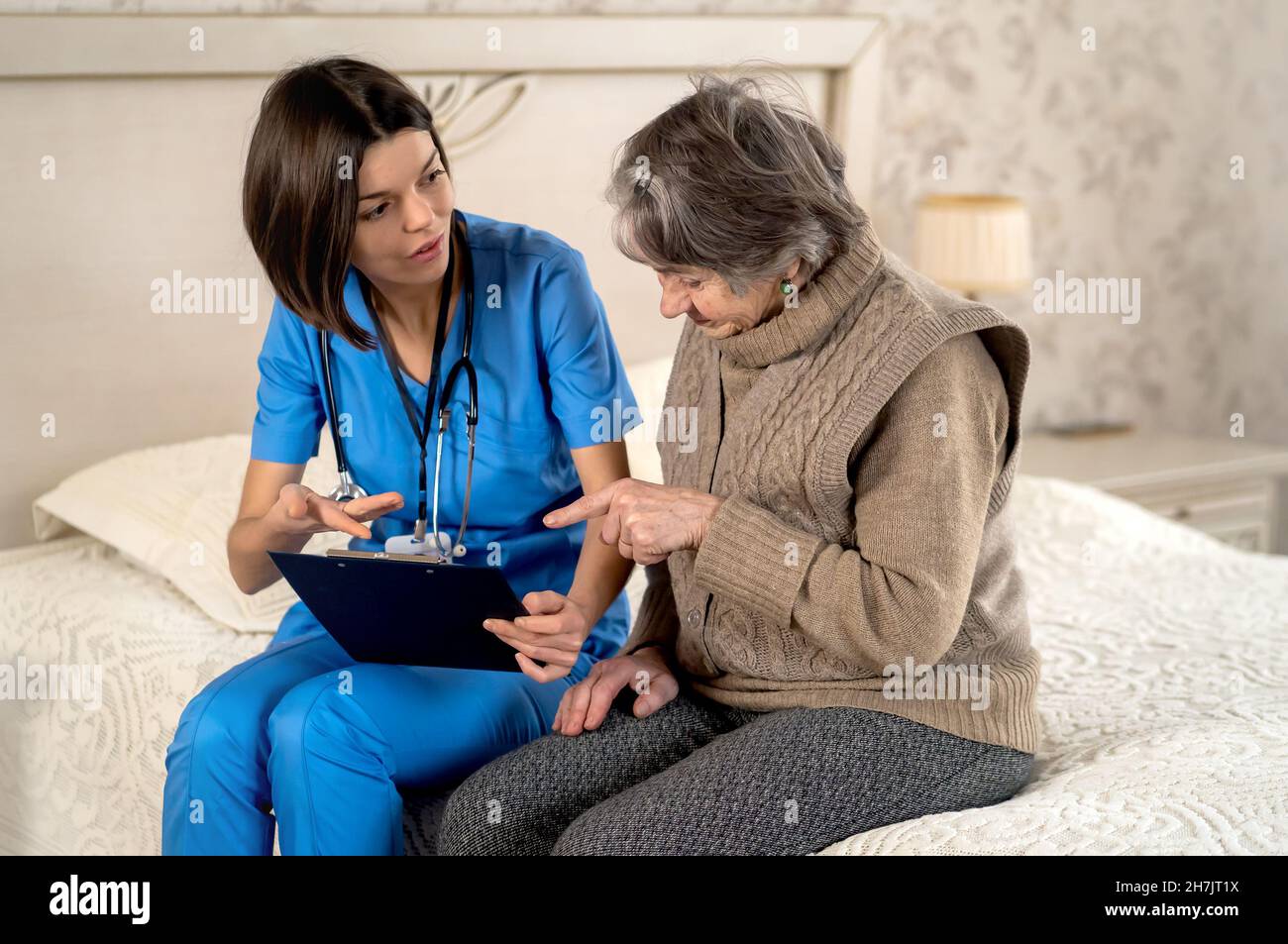 Young nurse is caring for an elderly 80 year-old woman at home. Stock Photo