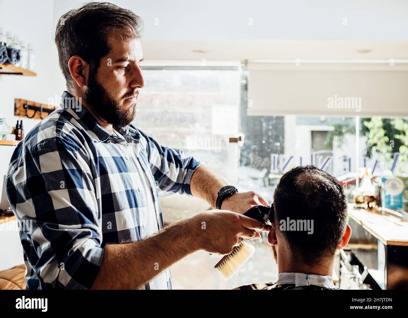 Barber cutting the client's hair. Process of trimming in the barbershop. Stock Photo