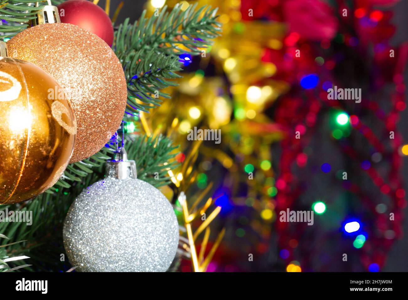 Christmas toys on the Christmas tree on the colorful lighting background. Beautiful glass Christmas decorations. Cool bright New Year's toys Stock Photo