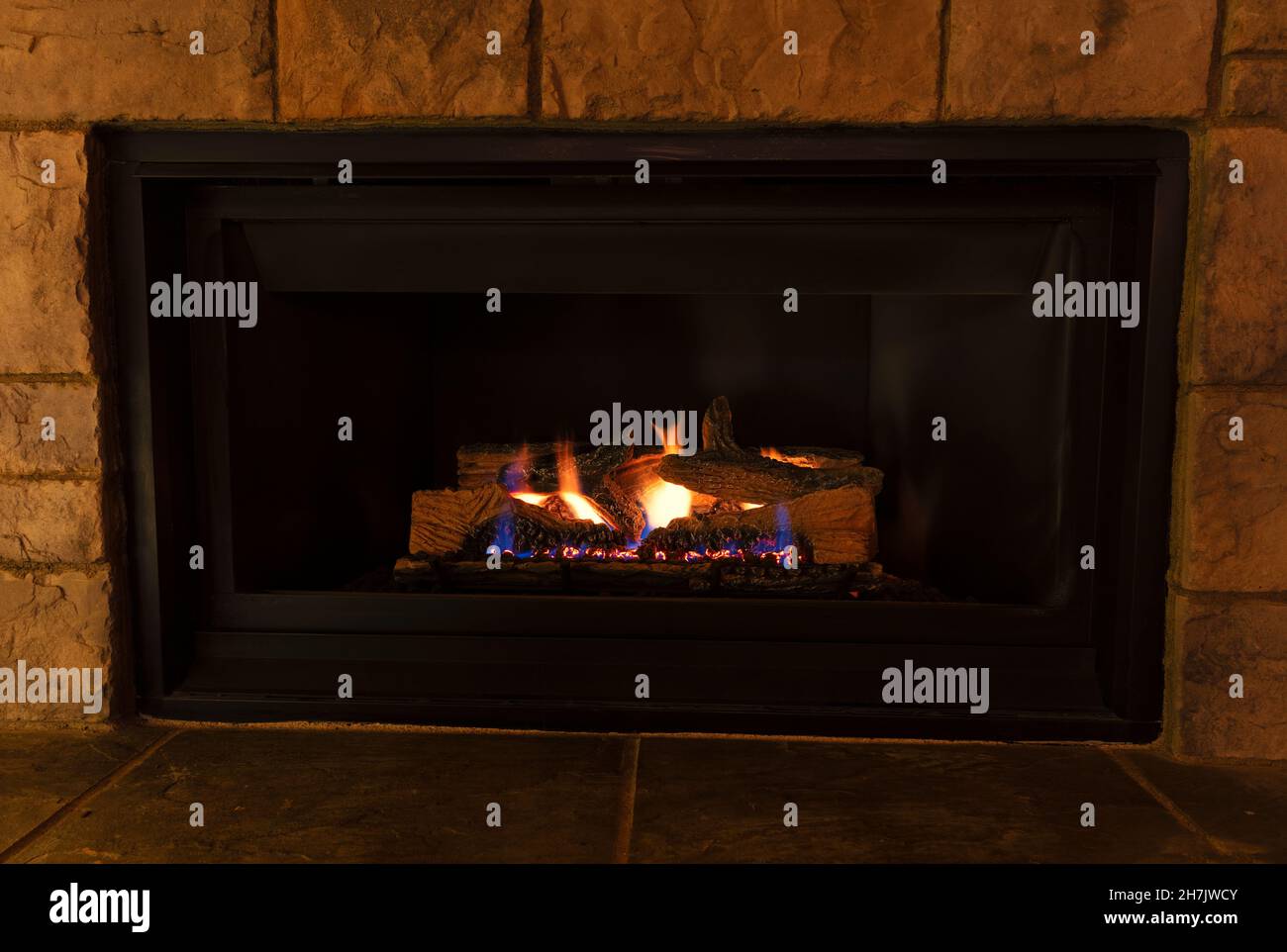 Burning natural gas fireplace during the evening at home Stock Photo