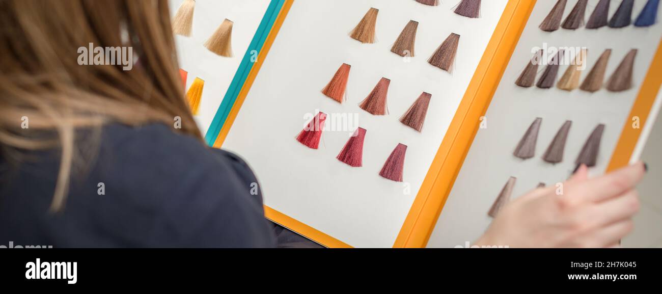 Young brunette woman choosing hair color from palette samples at the ...