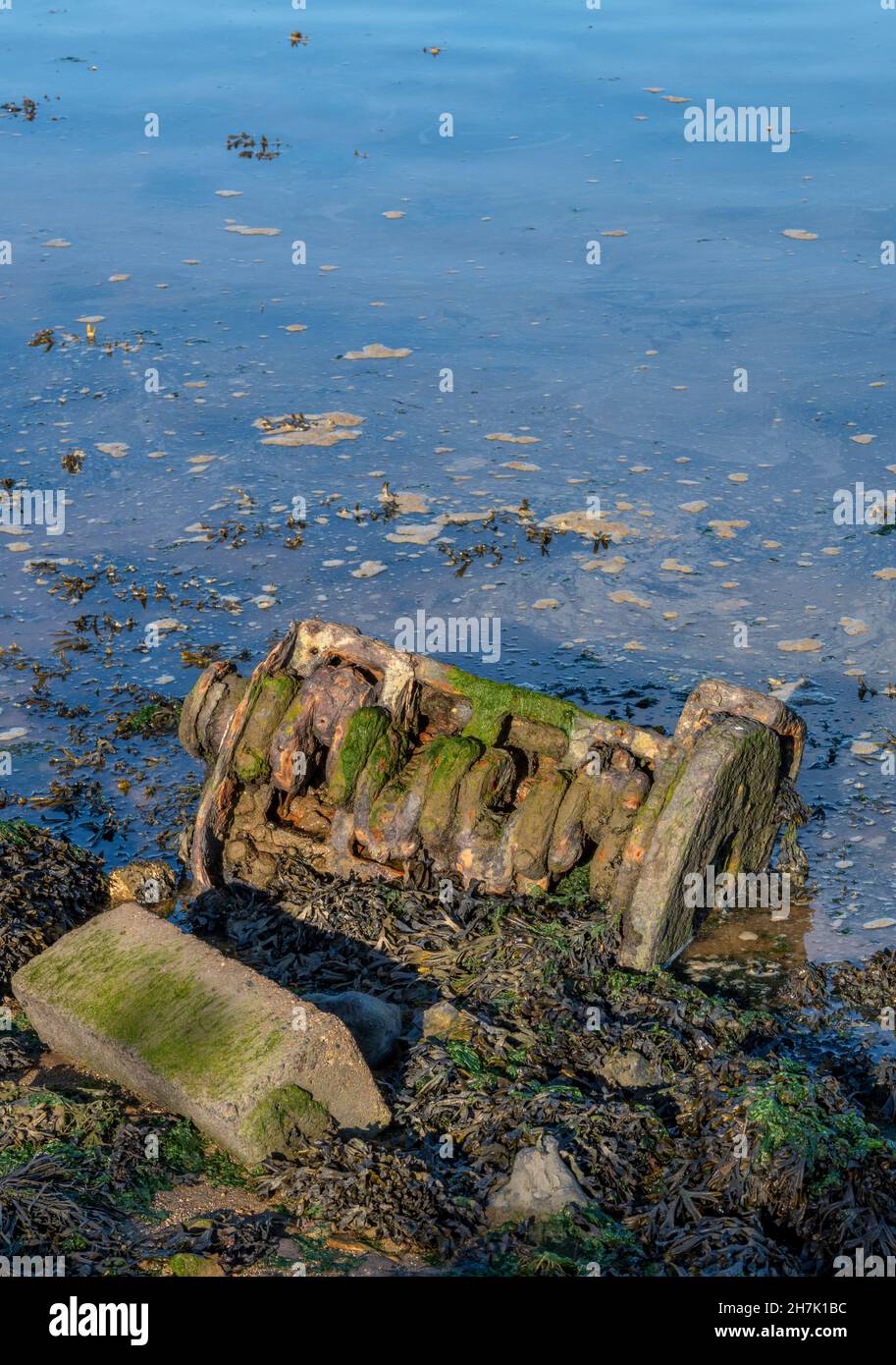 old engine on the beach causing pollution and leaking oil into the sea ...