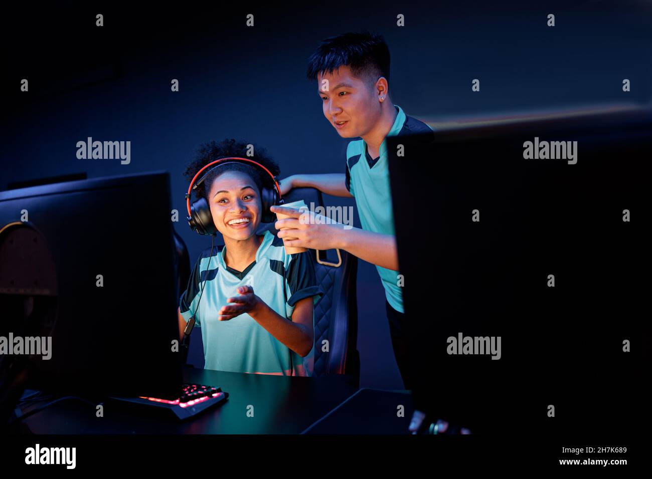 Teammate helps his friend to pass game in cyber club Stock Photo
