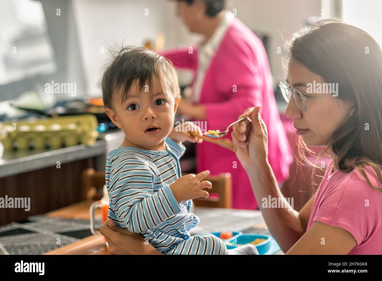 Latin baby boy eating breakfast sitting down at the kitchen table Stock Photo