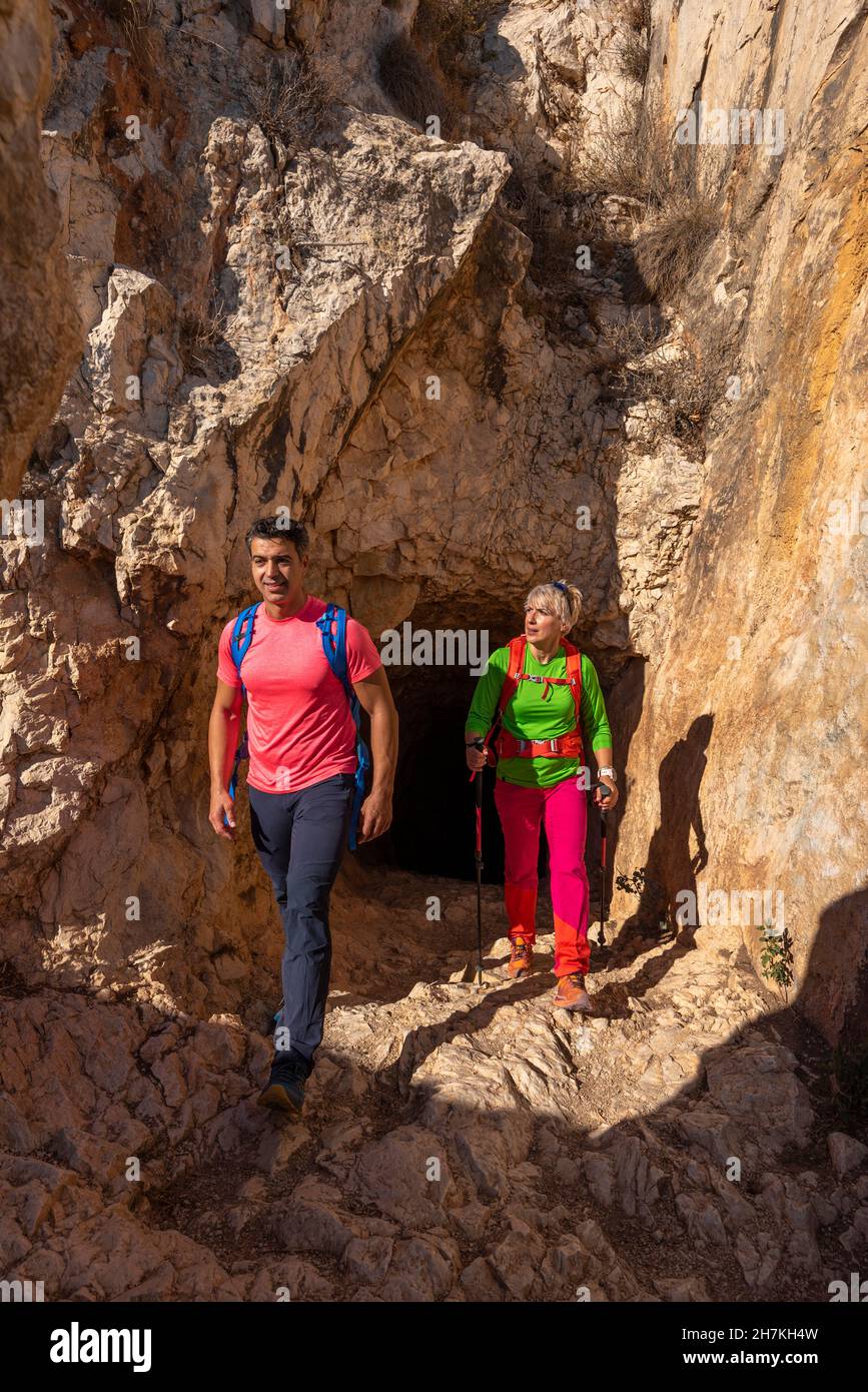 Couple hiking on mountain, coming out of a rock tunnel, Calpe, Alicante province, Spain Stock Photo