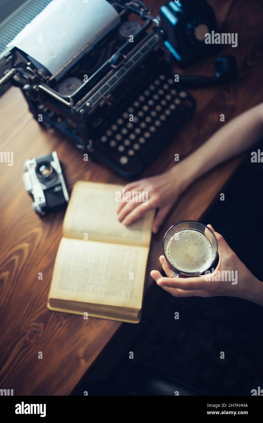 Woman holding glass of hot coffee and reading a book. Top view. Stock Photo