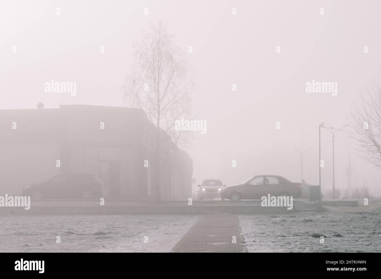 Silhouettes of cars and buildings in thick fog on a frosty cold morning in winter Stock Photo