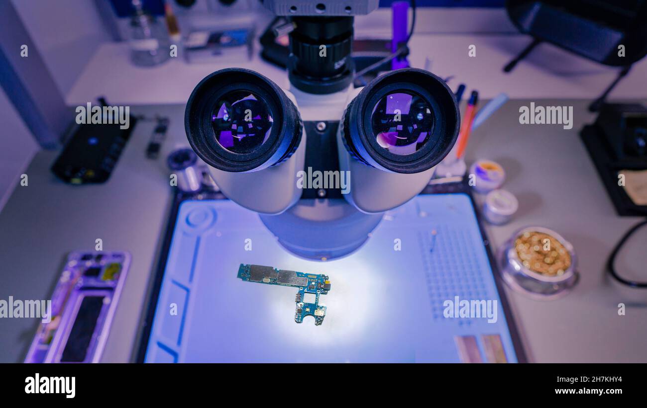 Computer chip under bright lighting in a laboratory, being inspected by a microscope Stock Photo