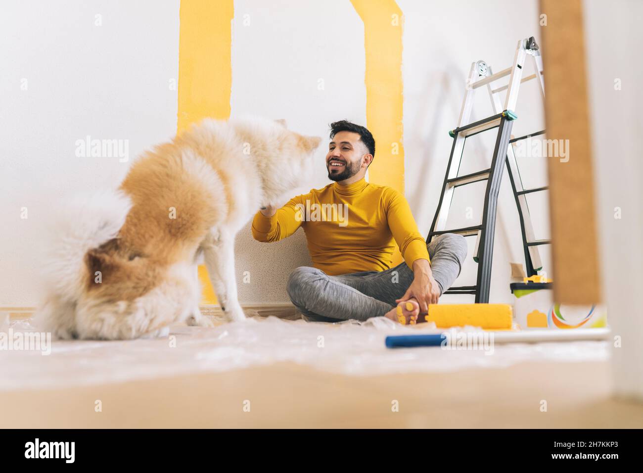 Happy handsome man with yellow paint on foot sitting at home Stock Photo