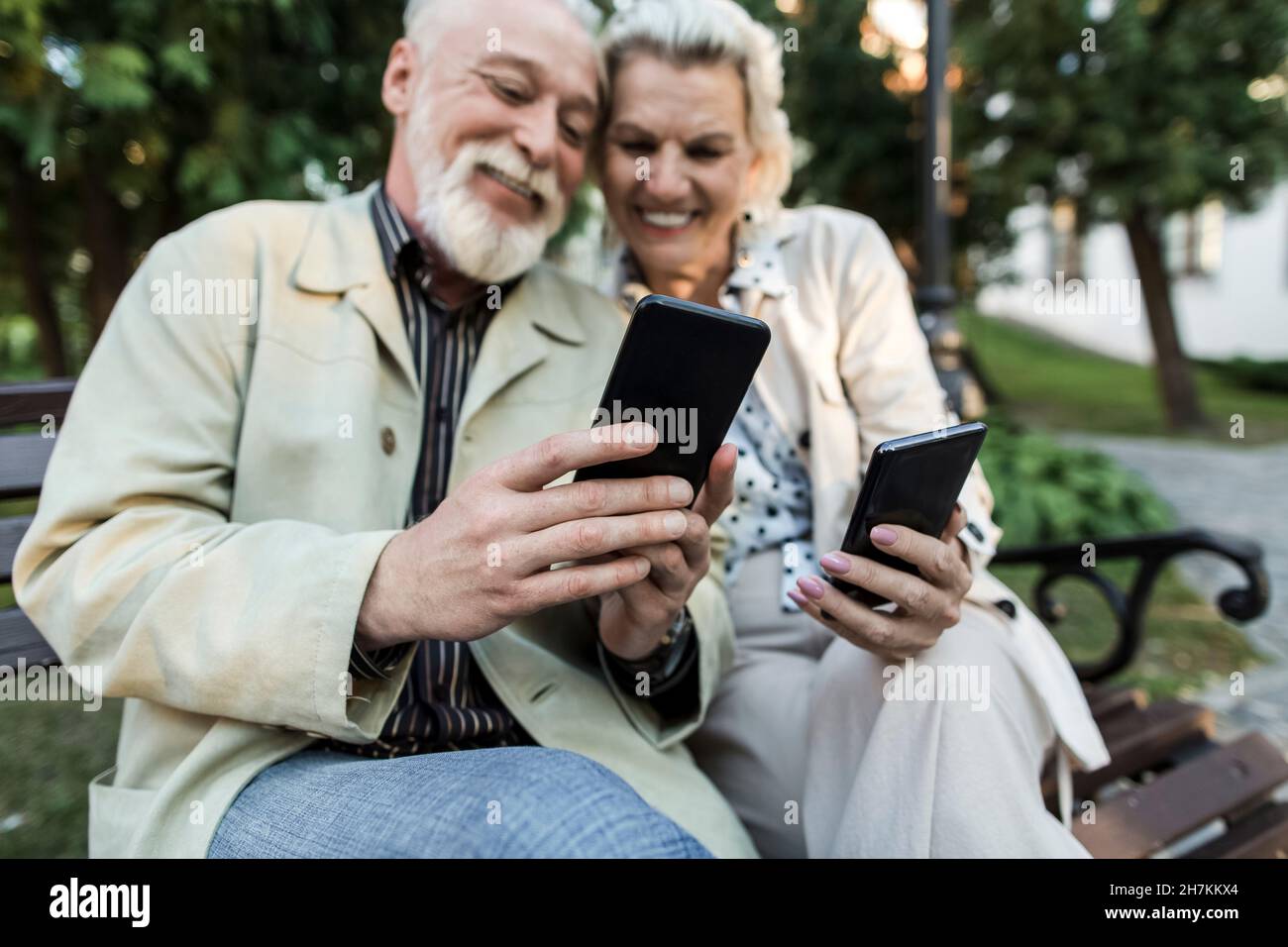 Couple using smart phone while sitting on bench Stock Photo