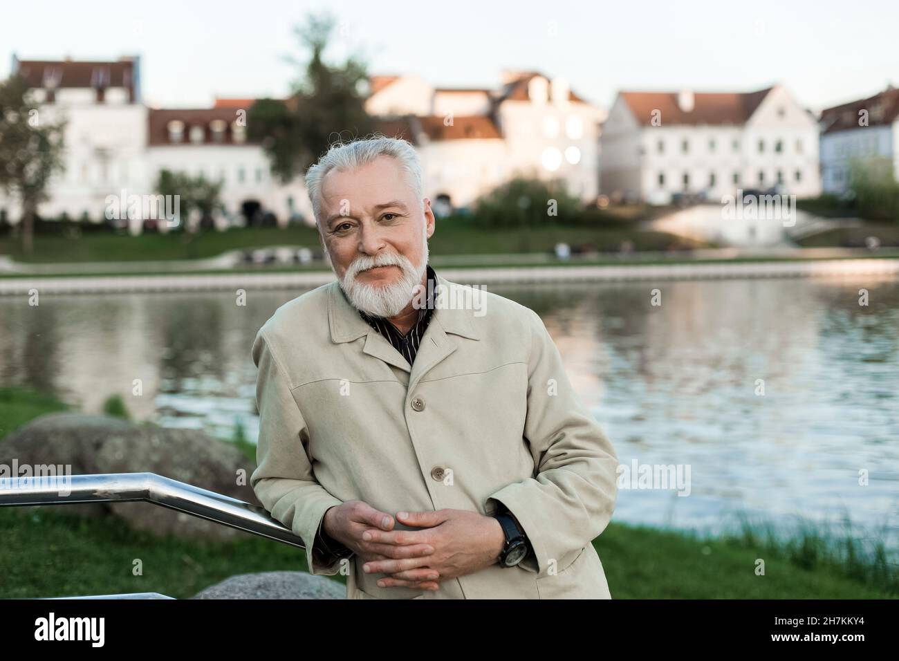 Mature man with hands clasped leaning on railing Stock Photo