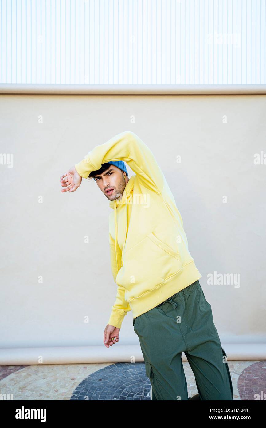 Young man dancing in front of beige backdrop Stock Photo