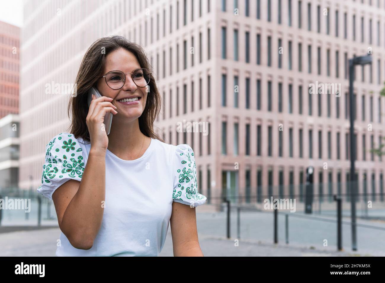Happy young working woman while talking on mobile phone Stock Photo