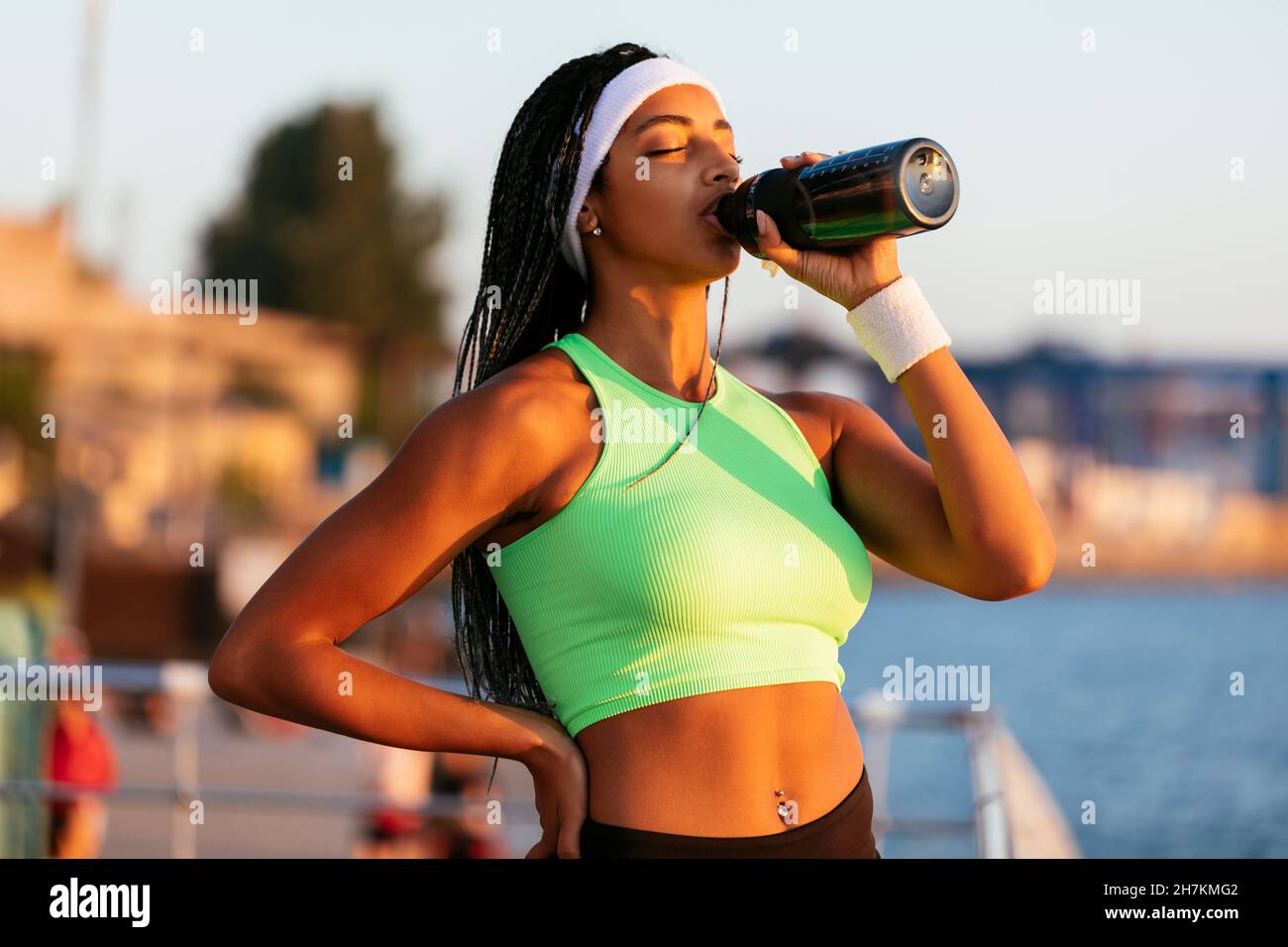Young female athlete with eyes closed drinking water from bottle Stock Photo